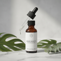 Dark glass dropper bottle of ingrown beard hair serum on marble surface
