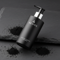Men's charcoal face wash dark packaging on slate background with activated charcoal powder
